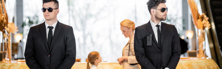 personal security, handsome bodyguards in suits and sunglasses protecting mother and child in hotel lobby, luxury lifestyle, woman and girl standing at reception desk, bannerの写真素材