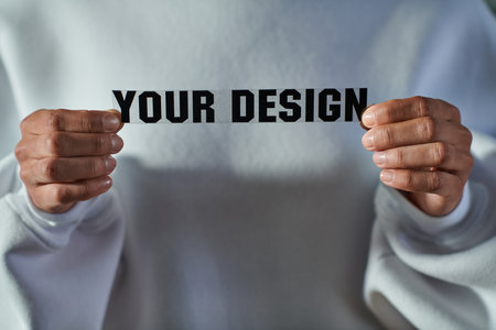 Cropped view of african american craftswoman in sweatshirt holding printing layer with your design lettering in print studio, focused business owner managing workshopの写真素材