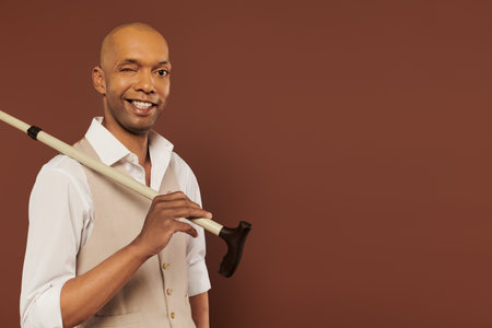 inclusion, myasthenia gravis syndrome, cheerful african american man holding walking cane, looking at camera, dark skinned, positivity, neurological disorder, physical impairmentの写真素材