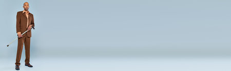 ptosis syndrome, full length of bold african american man with myasthenia gravis standing on grey background, dark skinned person in suit holding walking cane, diversity and inclusion, bannerの写真素材