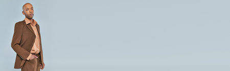 eye syndrome, bold african american man with myasthenia gravis standing with hand in pocket on grey background, dark skinned person in formal wear, diversity and inclusion, real people, bannerの写真素材
