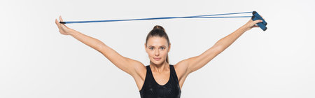 Fit sportswoman looking at camera while holding jump rope isolated on white, banner, sport concept