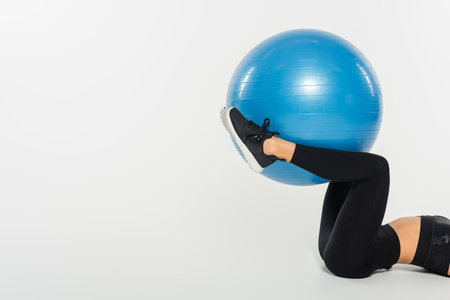 Cropped view of sportswoman exercising with fitness ball on white background, healthy fit conceptの写真素材