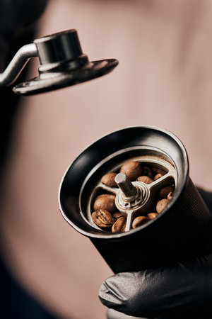 cropped view of barista holding manual coffee grinder with coffee beans, arabica, close up, energyの写真素材