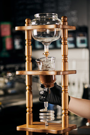 barista in black glove assembling cold drip coffee maker with ground coffee, alternative espresso brewの写真素材