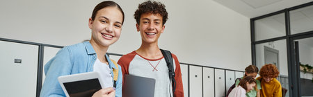 banner, teen classmates holding devices and looking at camera in school hallway, happy students