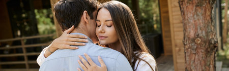 Young woman with closed eyes embracing brunette boyfriend near vacation house outdoors, banner