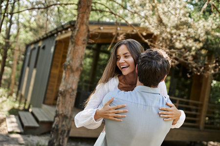 handsome man hugging happy woman in white sundress, vacation house near forest, romance and loveの写真素材