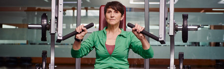 strong and motivated elderly woman exercising in gym, mature fitness, energy, active senior, banner