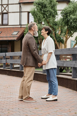 woman and bearded man holding hands, date, senior romance, happy elderly couple, full length