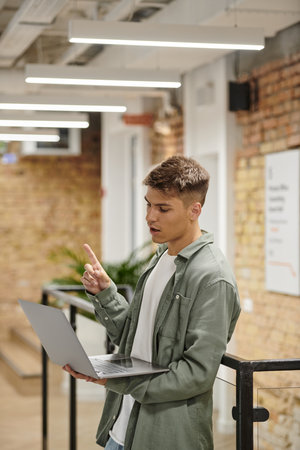 young man using laptop, video call, idea sign, modern coworking, office, generation z, startupの写真素材