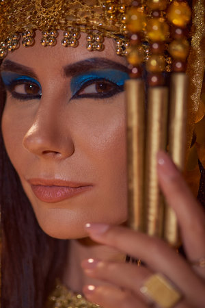 Portrait of beautiful woman with bold makeup and traditional egyptian headdress looking at cameraの写真素材