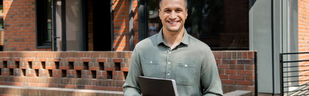 successful and confident real estate broker smiling at camera near contemporary cottage, banner
