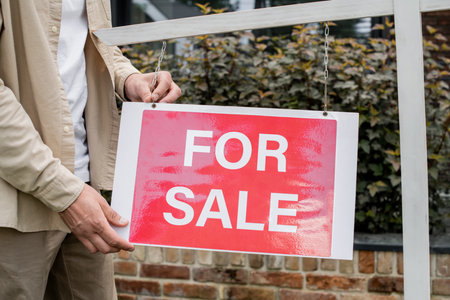 partial view of real estate agent hanging signboard with for sale lettering outdoorsの写真素材
