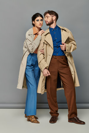 outerwear, couple in trench coats, fashion shot, stylish man and woman, grey background, trendsの写真素材