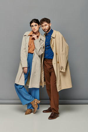 trendy couple in trench coats, fashion shot, man and woman, outerwear, grey background, styleの写真素材