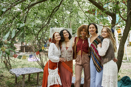 positive and multiethnic women in boho outfit looking at camera in retreat centerの写真素材