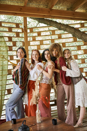 multiethnic women in stylish boho clothes standing and looking at camera in retreat centerの写真素材