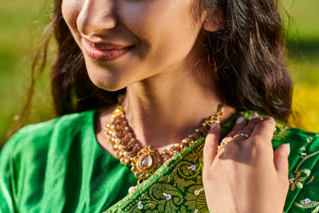 cropped view of smiling young woman in green sari posing and standing outdoorsの写真素材