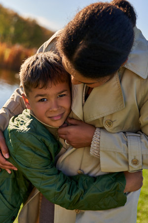 woman calming upset boy, african american mother and child, family bonding, autumnal nature
