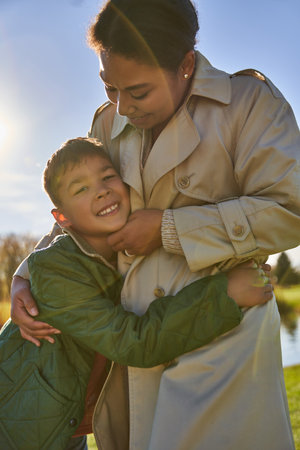 autumnal sunny day, happy african american woman hugging son, african american family, fall seasonの写真素材