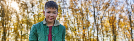 happy african american boy in outerwear looking at camera in autumn park, fall season, bannerの写真素材