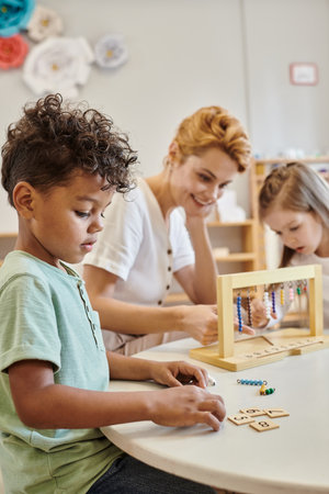 african american boy counting and using tiles, montessori concept, teacher and girl playing game