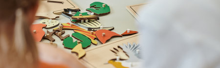 cropped view of didactic materials on table near blurred kids in montessori school, bannerの写真素材