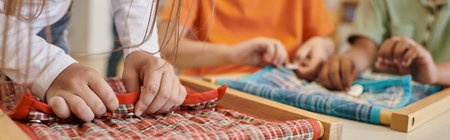 partial view of child playing with cloth and buttons in montessori school, bannerの写真素材