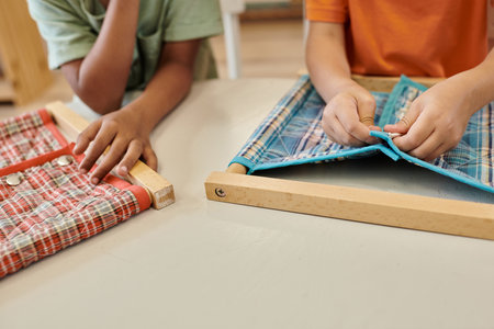 cropped view of multiethnic kids playing with cloth and buttons during lesson in montessori schoolの写真素材