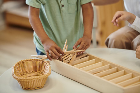cropped view of african american boy holding wooden sticks near girl in montessori schoolの写真素材