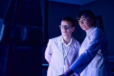 futuristic concept, middle aged woman scientist and intern near new equipment in discovery centerの写真素材