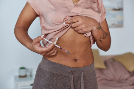 cropped view, african american woman making hormonal injections in belly, tattoo, pregnancy conceptの写真素材