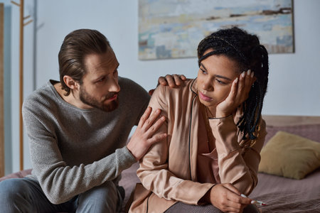 abortion concept, man calming down african american woman with pregnancy test, interracial coupleの写真素材