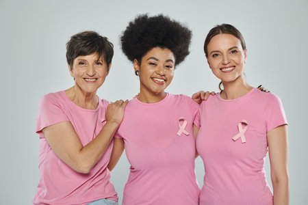 breast cancer awareness, interracial women smiling on grey backdrop, different generations, portraitの写真素材