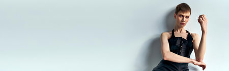 androgynous model in black corset posing on grey backdrop, queer fashion, lgbtq, edgy style, bannerの写真素材