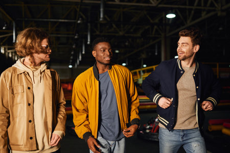 multicultural friends smiling and walking together inside of karting track, motorsport hobbyの写真素材