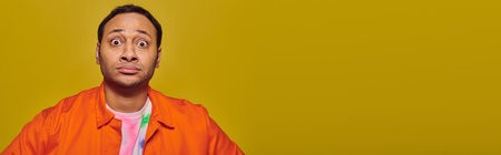 shocked indian man with eyes wide open looking at camera isolated on yellow, face expression, banner