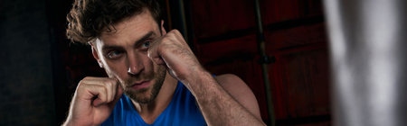 resilient unshaven man exercising and boxing in darkness on urban street, bannerの写真素材