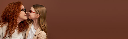 two generations, happy redhead mother and kid in sunglasses on brown backdrop, face to face, bannerの写真素材