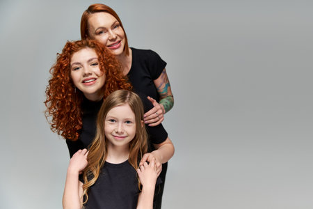 generations concept, delightful family with red hair posing in matching attire on grey background
