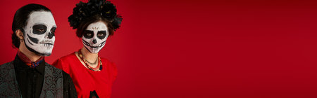 dia de los muertos couple, woman in eerie skull makeup and black wreath near man on red, bannerの写真素材