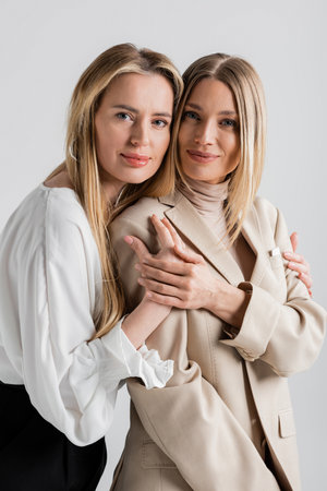 portrait of two stylish cute sisters hugging each other and looking at camera, fashion conceptの写真素材
