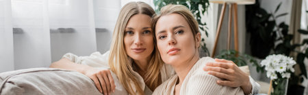 portrait of classy sisters in trendy attire hugging looking at camera, family bonding, bannerの写真素材