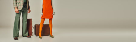 cropped view of retro couple in orange dress and plaid blazer near vintage suitcases on grey, banner