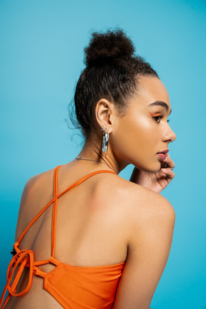 close up back view of attractive african american model in orange trendy outfit looking awayの写真素材