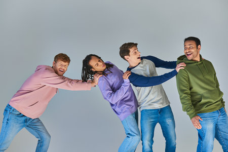 four smiling happy men in casual urban outfit having great time on grey backdrop, cultural diversityの写真素材