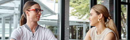 two smiling coworkers man and woman looking at each other with glass backdrop, coworking, bannerの写真素材