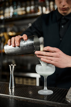 cropped view of bartender with cocktail shaker making milk punch in bar, cocktail artistryのeditorial素材