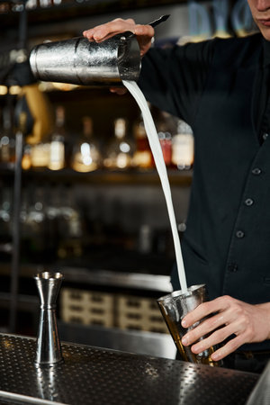 cropped view of bartender with cocktail shaker and milk pitcher preparing craft drink in barのeditorial素材